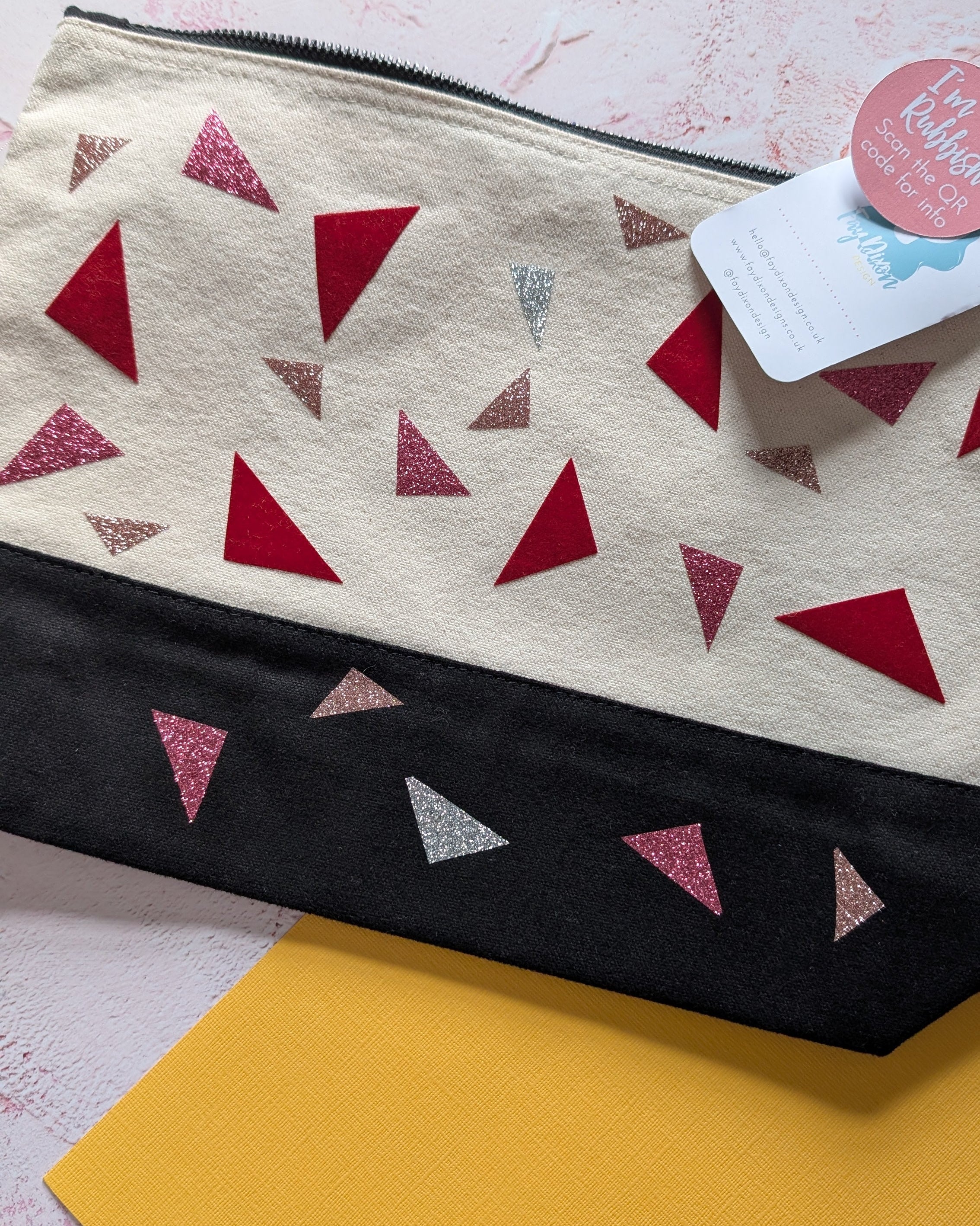 Pouch with red triangle pattern on beige fabric, black border, and pink triangle design on yellow background.