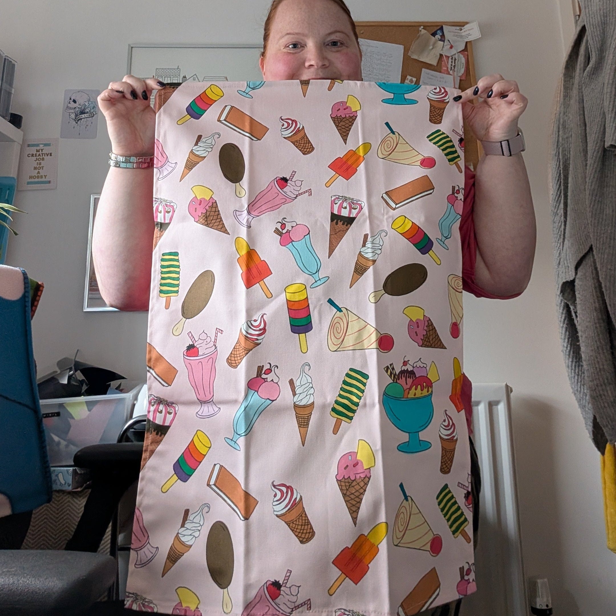 Fay holding a colourful teatowel with ice cream pattern in a room.