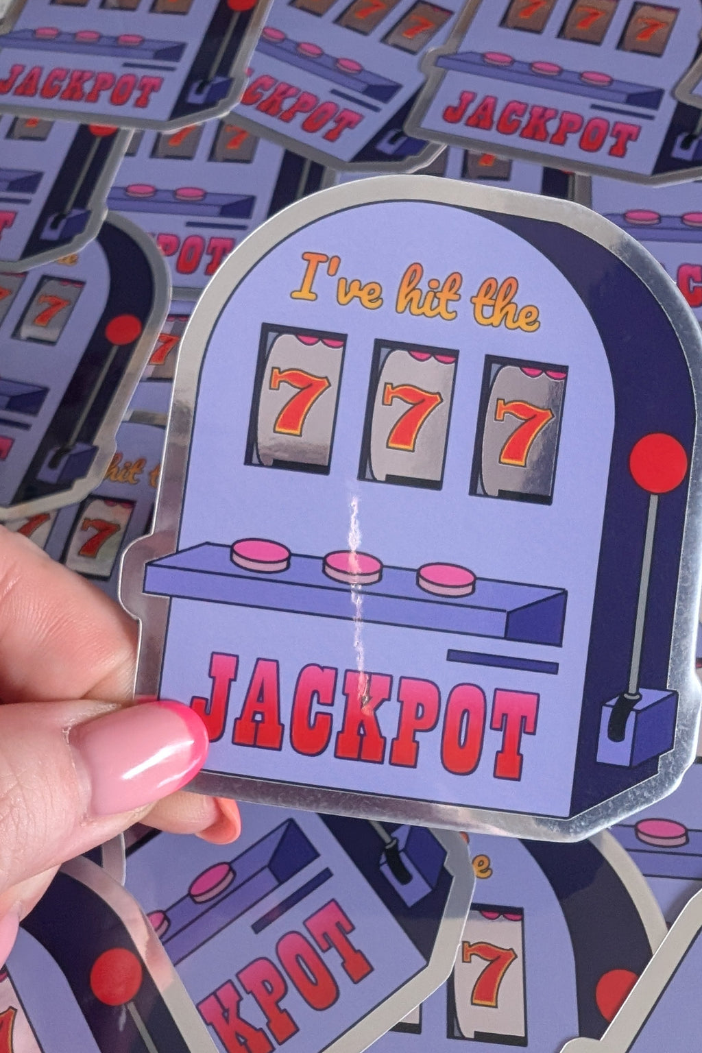 Sticker of a slot machine with 'I've hit the jackpot' text held by a hand.